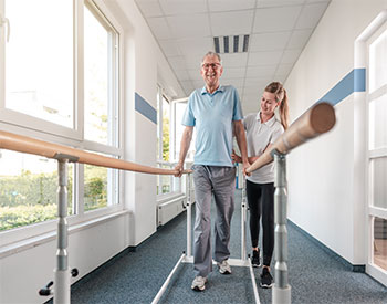 Senior Patient and physical therapist in rehabilitation walking exercises.